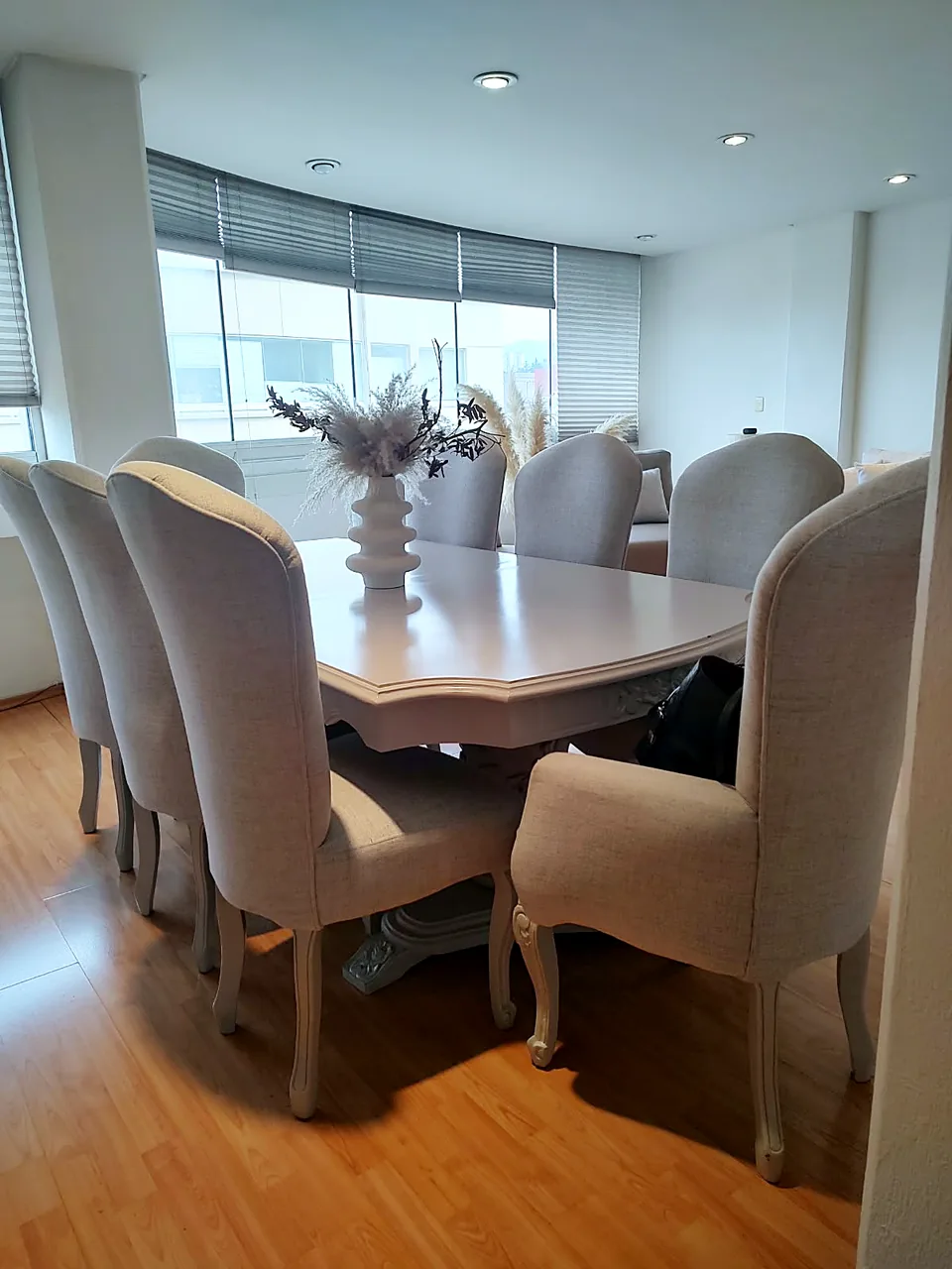Comedor con sillas tapizadas en tela gris en un departamento remodelado