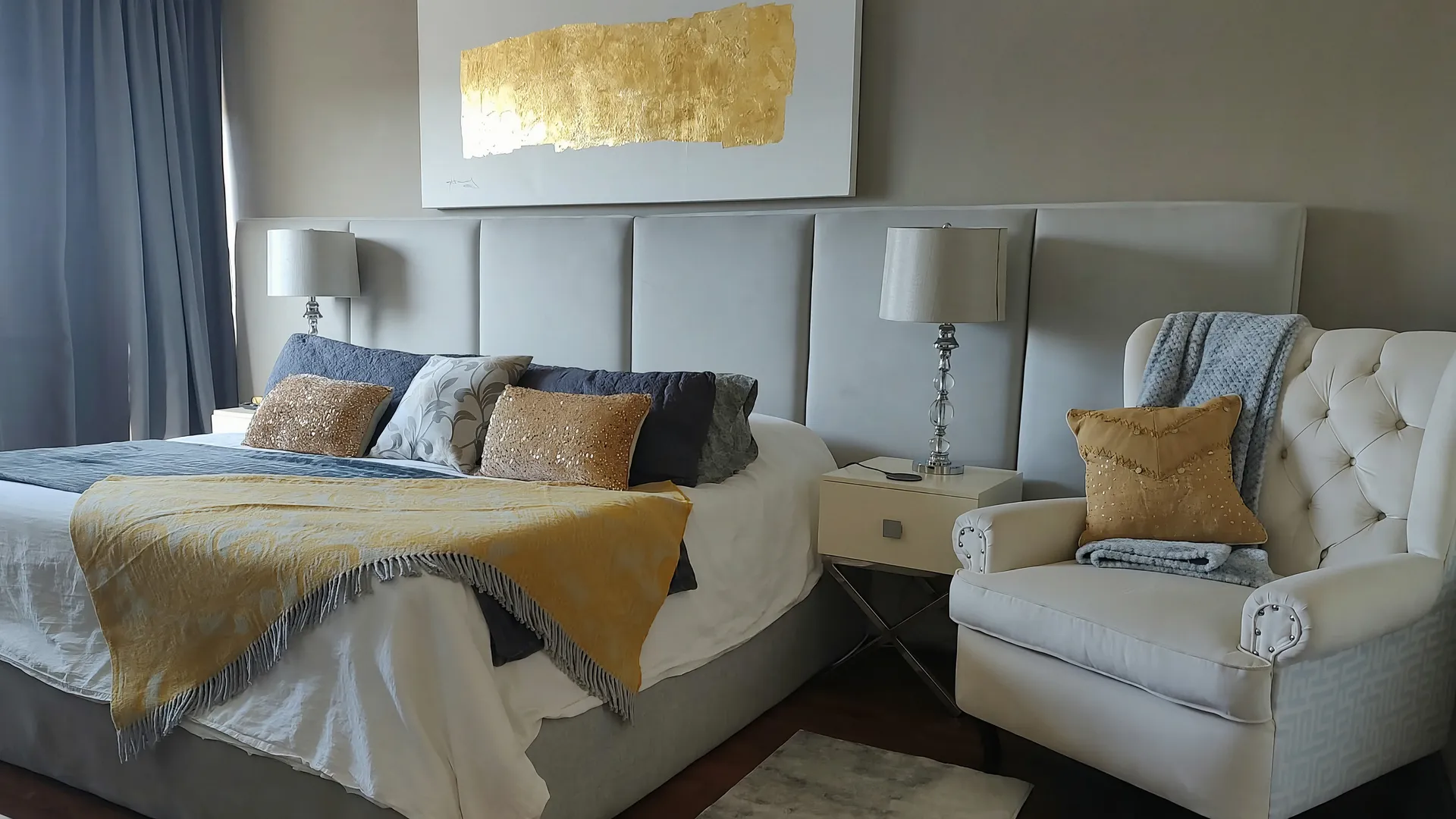 Recámara remodelada por Velvet con cabecera tapizada de muro completo y sillón capitonado